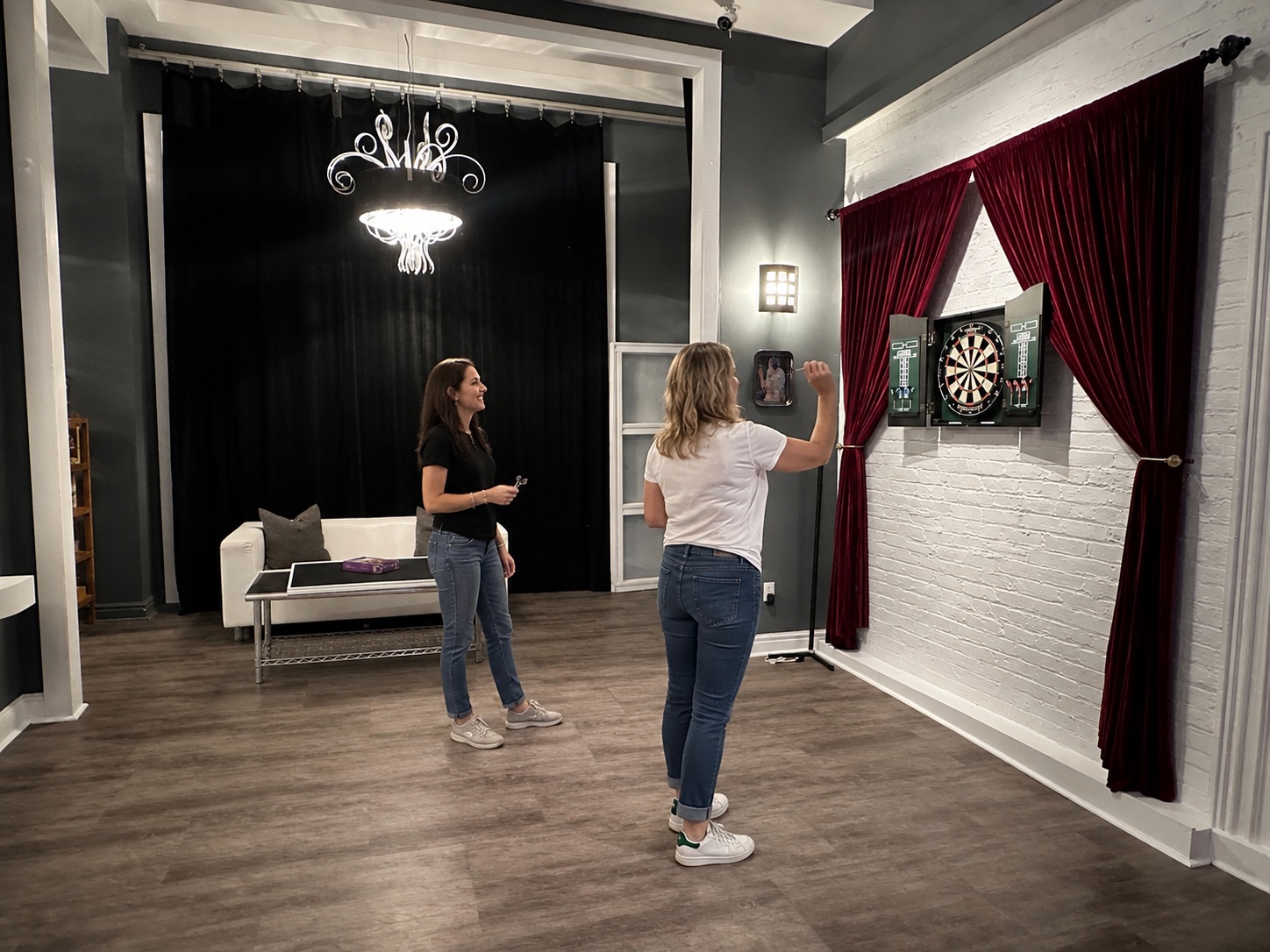 Two women enjoying a game of darts in the Bridge & Bloom lounge